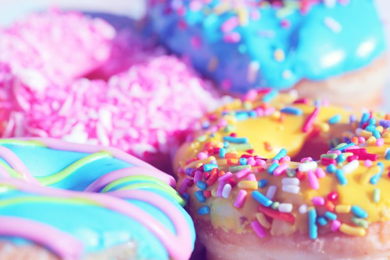 Colorful glazed donuts with sprinkles, used as a hero image for an article explaining how sugar and hormones interact for women over 40.