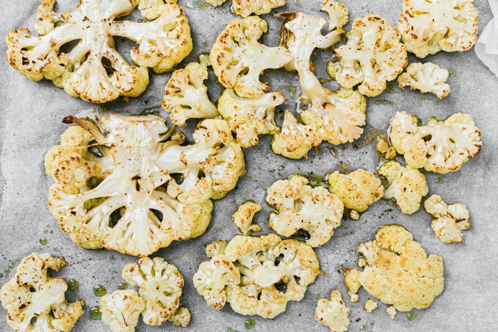 Roasted cauliflower slices on a baking sheet, used to show foods to balance hormones naturally for women over 40.