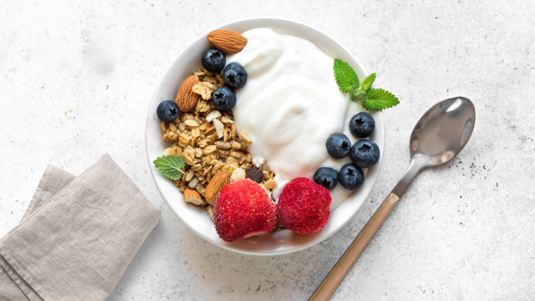 Bowl of yogurt with granola, almonds, and berries showing probiotic foods that support gut health and hormone balance for women over 40.
