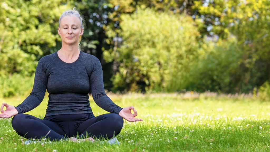 Woman practicing yoga outdoors to reduce stress and support gut health and hormone balance naturally