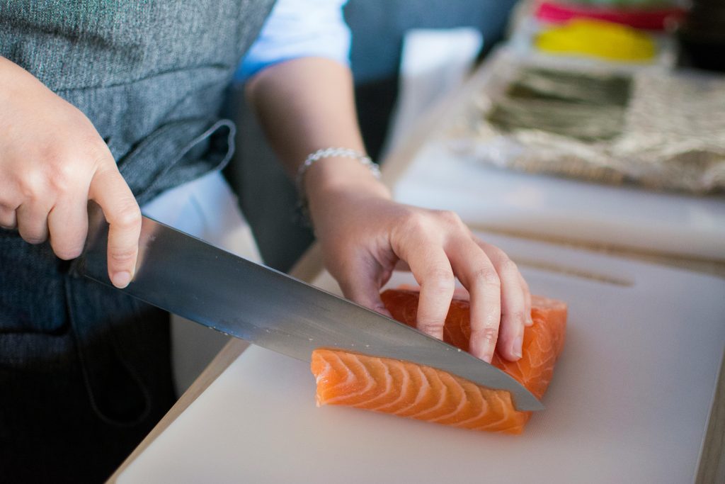 Person slicing fresh salmon on a cutting board as part of a hormone balance diet plan for women.