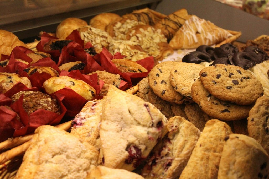 Assortment of processed carbs including pastries, muffins, scones, and cookies, illustrating foods high in refined flour and sugar that are among the worst foods for hormone health.