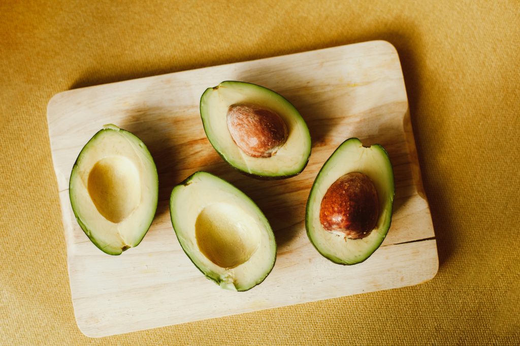 Halved avocados on a wooden cutting board, showing the healthy fats used in hormone balancing smoothies for women to support steady energy and hormone health.