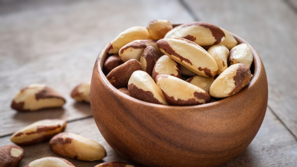 Brazil nuts in a wooden bowl, a nutrient-rich snack that supports hormone balance and steady energy.