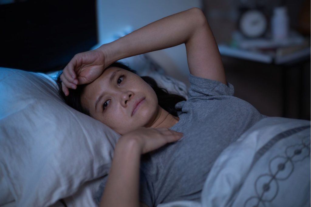 Woman lying awake in bed at night, illustrating how sleep affects hormones and why nighttime wake-ups may be linked to cortisol and hormone imbalance.