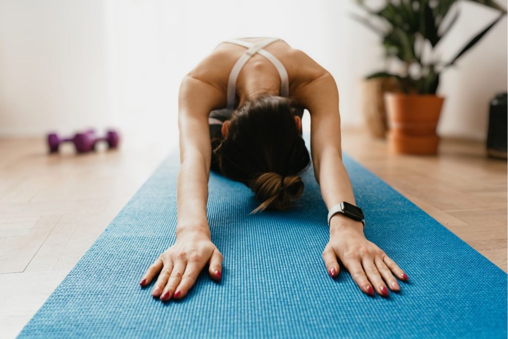 Woman practicing gentle yoga on a mat, illustrating daily habits to balance hormones naturally through movement that reduces stress and supports hormone health after 40.