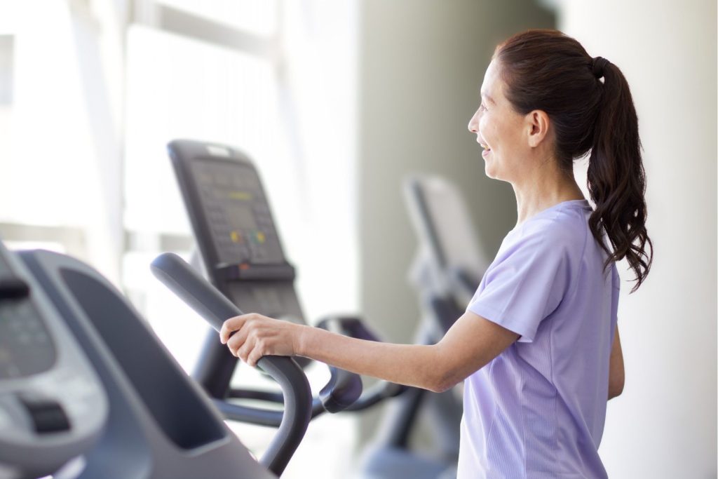 Woman using an elliptical machine for low-impact cardio, supporting gentle exercise and hormone-friendly workouts after 40.