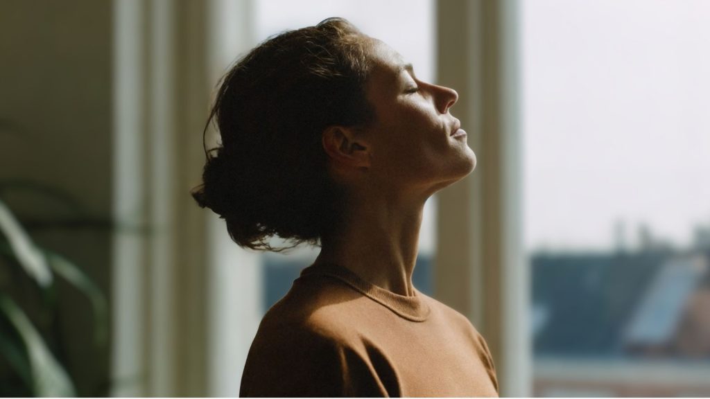 Woman practicing calm breathing in natural light, representing natural ways to reduce cortisol and support stress balance after 40.