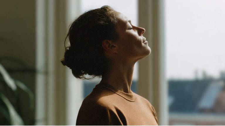Woman practicing calm breathing in natural light, representing natural ways to reduce cortisol and support stress balance after 40.