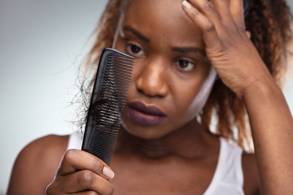 Woman looking concerned at hair shedding in comb after stopping birth control