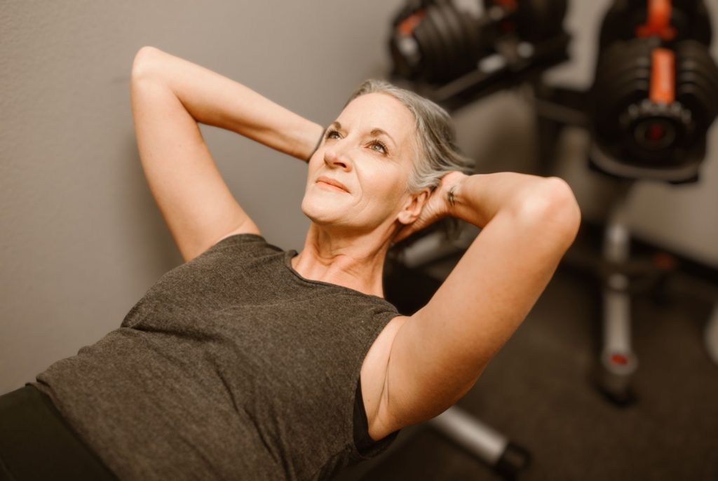 Woman over 50 doing strength training to support muscle, metabolism, and hormone health after menopause.