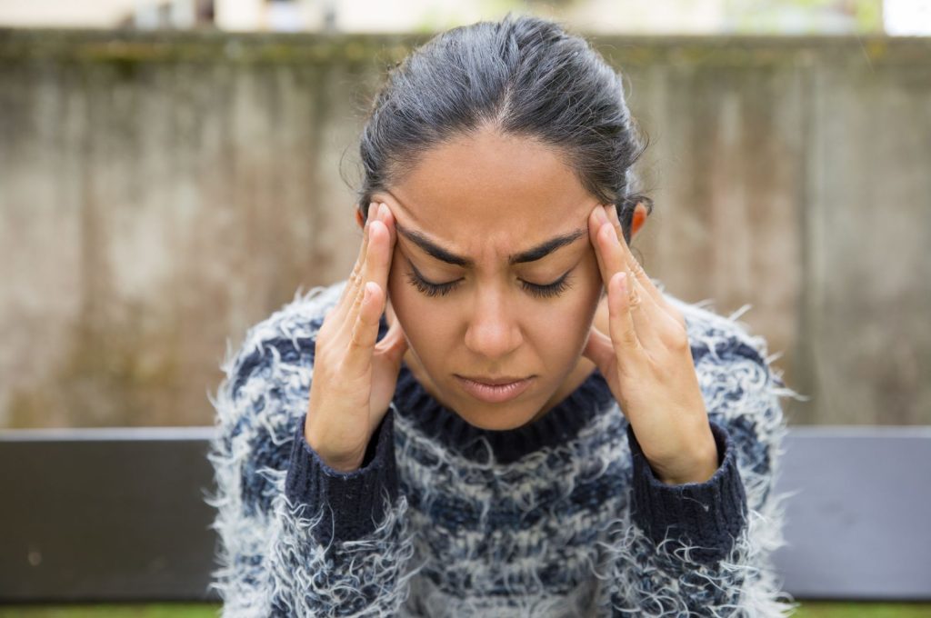 Woman experiencing head tension and discomfort, a common symptom of perimenopause hormone changes.