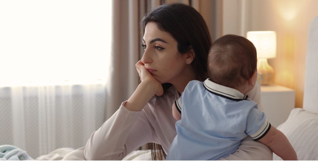Woman holding a baby in a quiet moment, reflecting on postpartum hormone imbalance and recovery over time