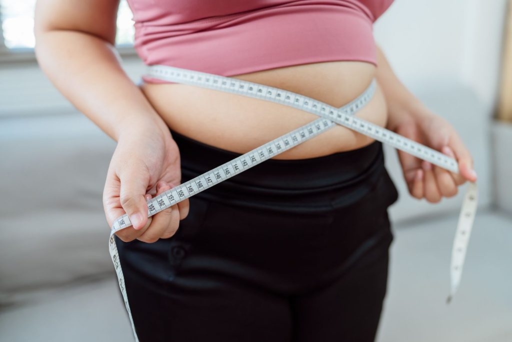 Woman measuring belly fat with tape measure, representing hormone imbalance weight gain belly fat after 40.