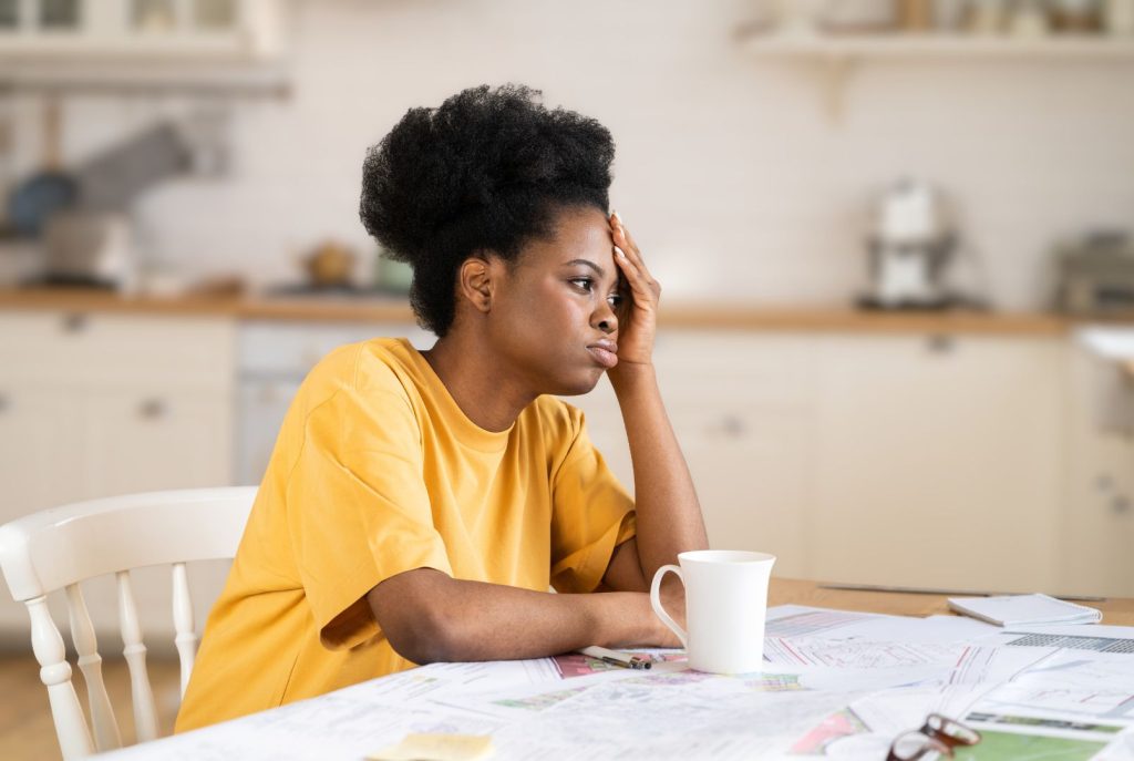 Woman over 40 feeling stressed and overwhelmed at table due to mood swings from hormone imbalance